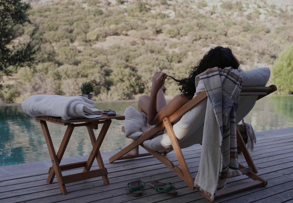 Luxurious Turkish beach towels draped over wooden loungers beside a serene pool, showcasing Minoa Home’s sustainable summer essentials for coastal, resort, or poolside living.