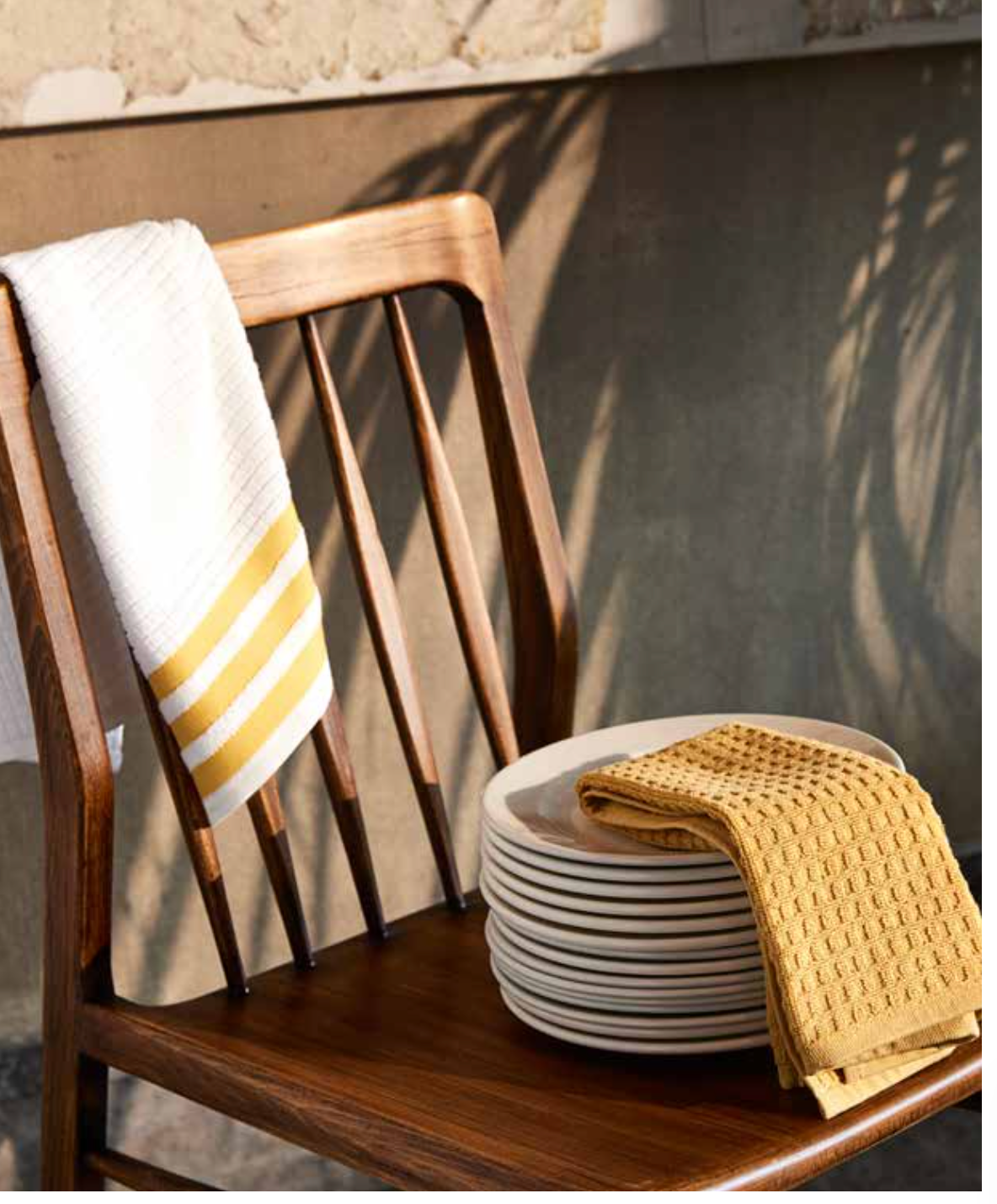 Kitchen Towel - Nova in mixed yellow and white, with one towel hanging over a chair and the other neatly placed on a plate, showcasing its soft cotton fabric and vibrant design