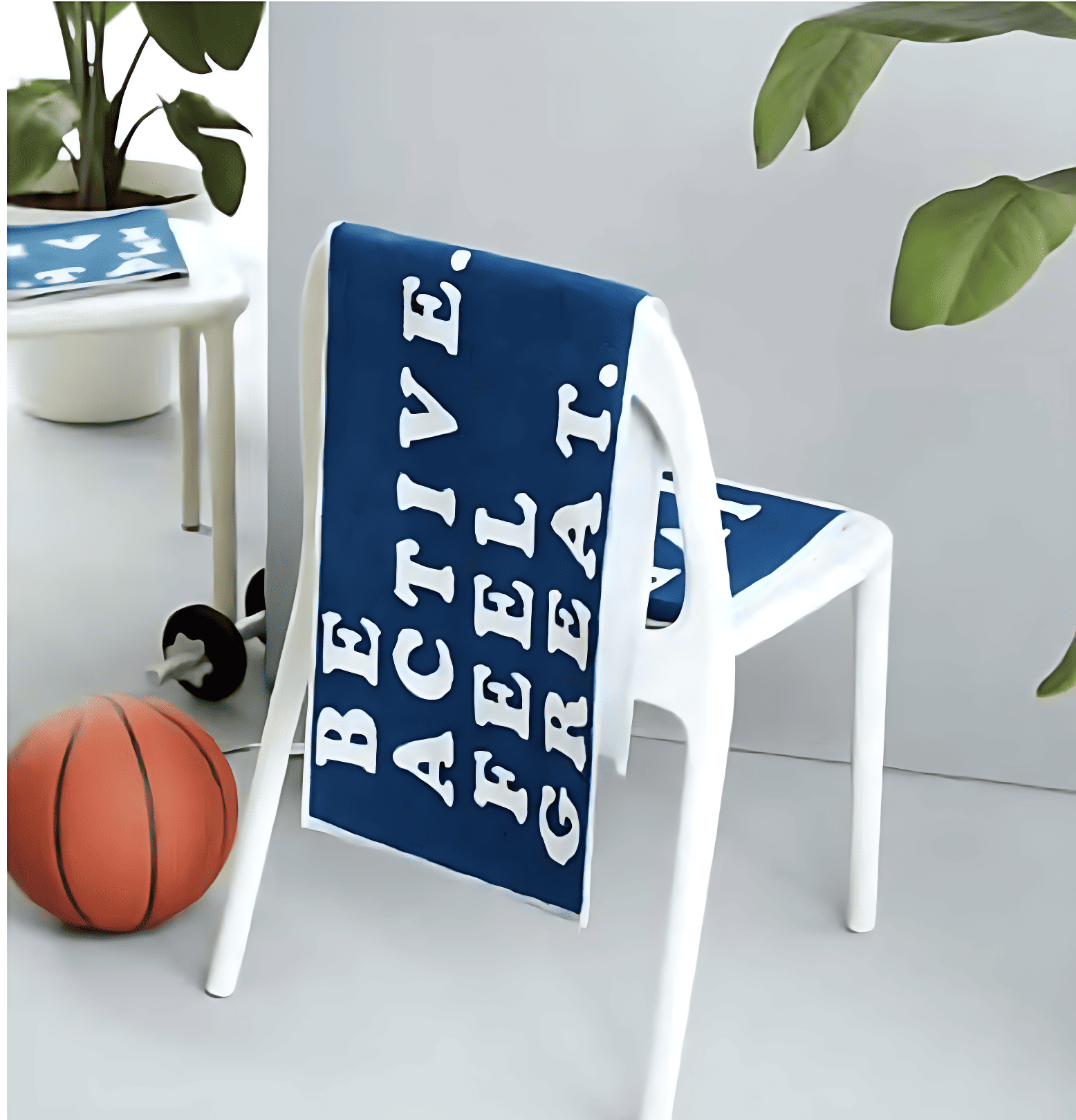 Blue towel with 'Be Active. Feel Great.' text on a white chair, with a basketball and plant in the background.