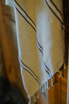 Blue and white eco friendly Anakao 215 gram Aegean Cotton and Linen Turkish towel hanging on wooden wall highlighting organic bath towel quality