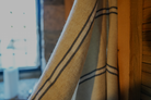Blue and white Anakao 215 gram Aegean Cotton and Linen Turkish towel hanging on the wall showcasing the soft texture of an organic bath towel