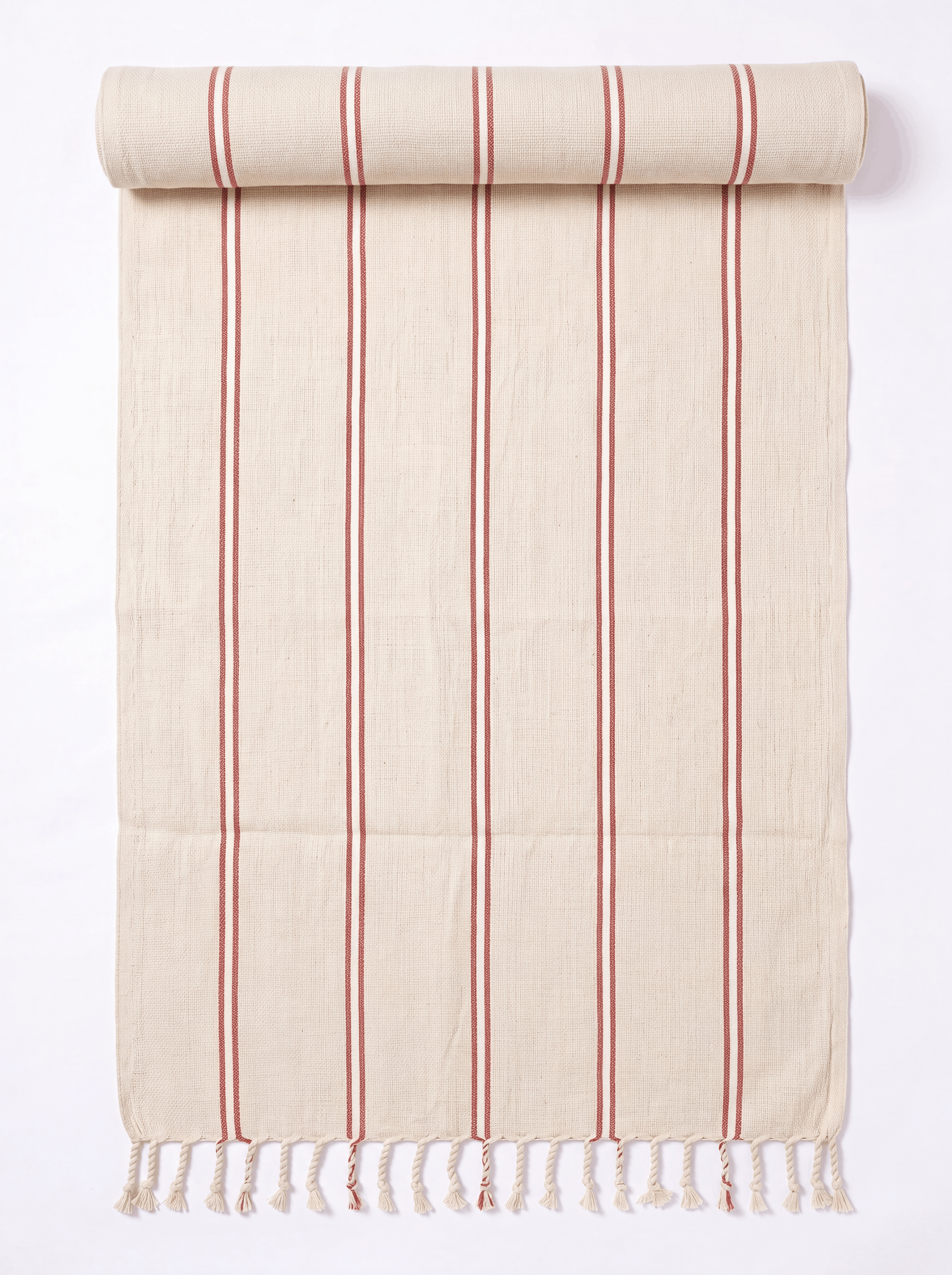 A cream-colored cotton towel with vertical red stripes and fringed tassels on one end, shown partially rolled at the top against a white background.