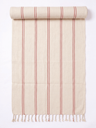 A cream-colored cotton towel with vertical red stripes and fringed tassels on one end, shown partially rolled at the top against a white background.