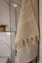 Beige towel with tassels hanging on a bathroom wall