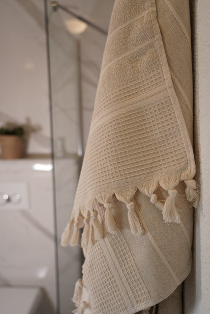 Beige towel with tassels hanging on a bathroom wall