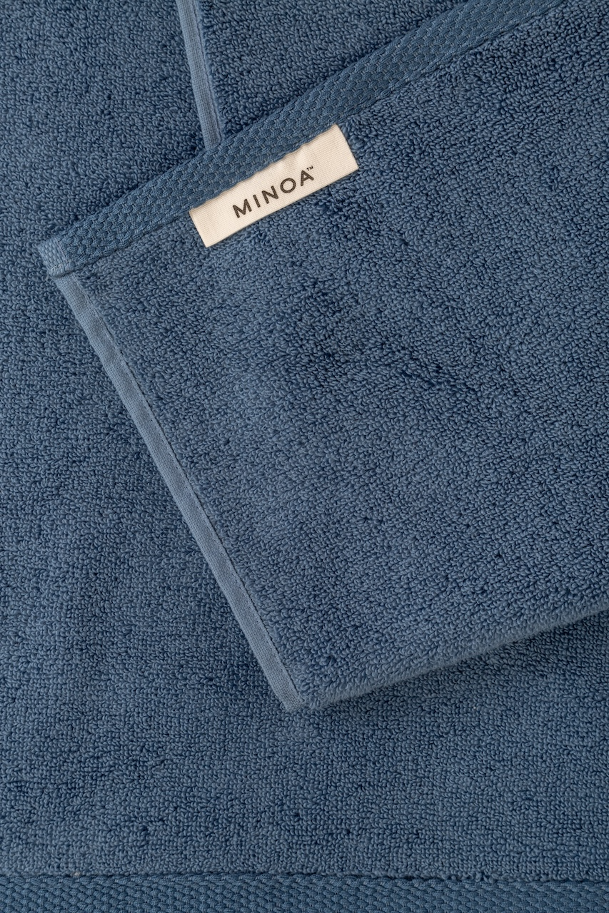 Blue towel with Minoa label on a matching background