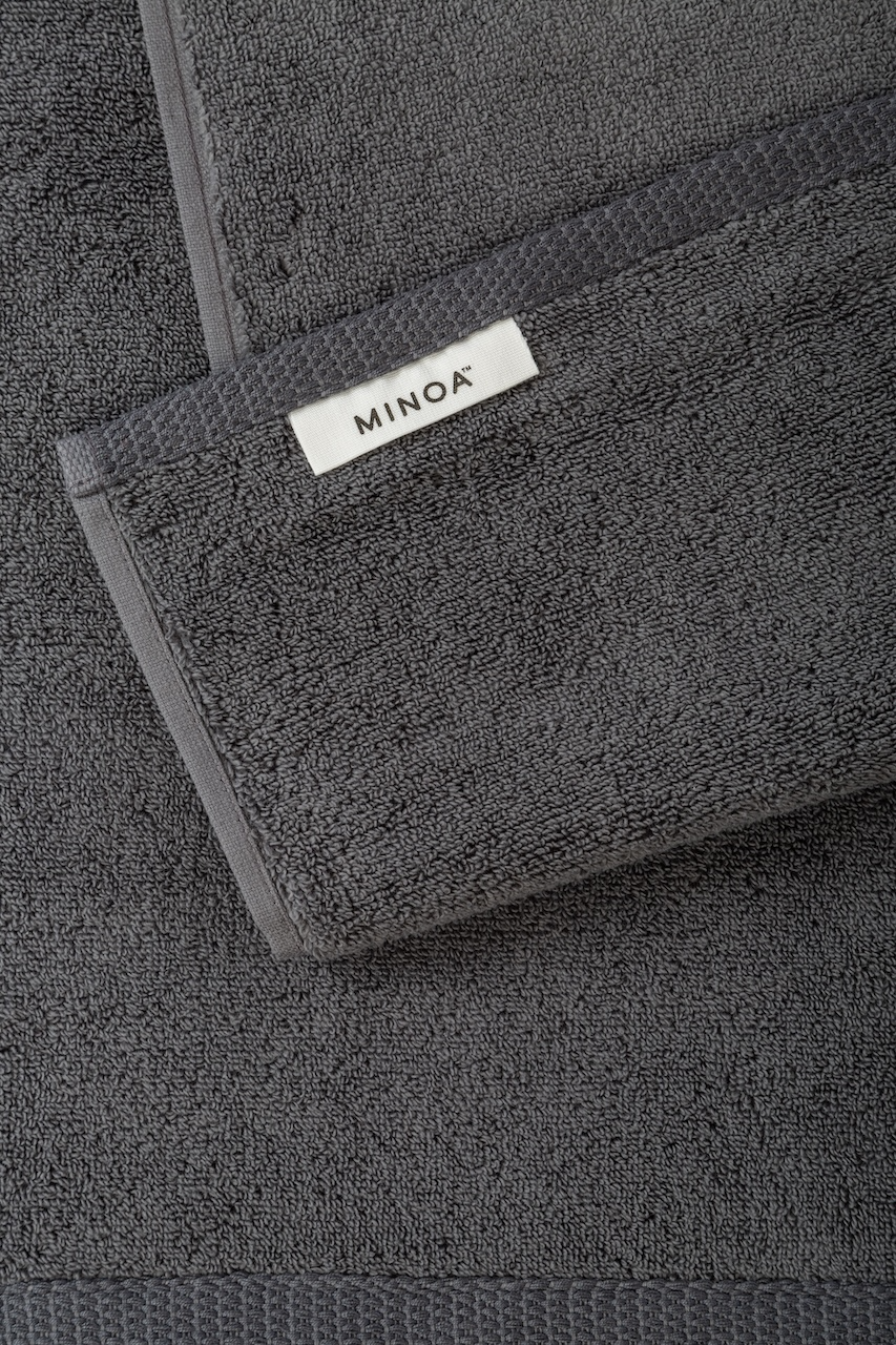 Dark gray towel with Minoa logo on a matching background