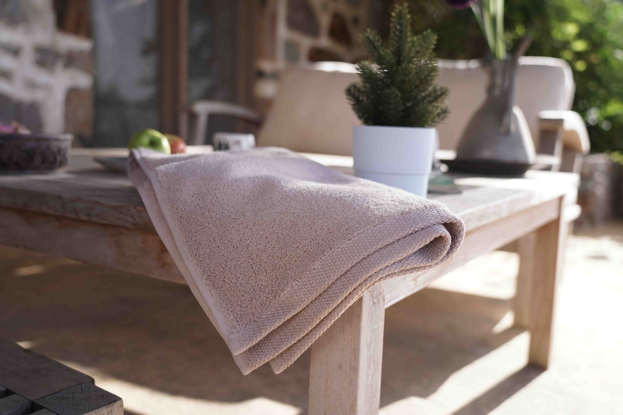 Minoa USA Canada sustainable organic bath towels Plush Lite Aegean Cotton bath towel pack of four with a greenish plants background, highlighting soft texture, premium quality, and natural eco-friendly vibe