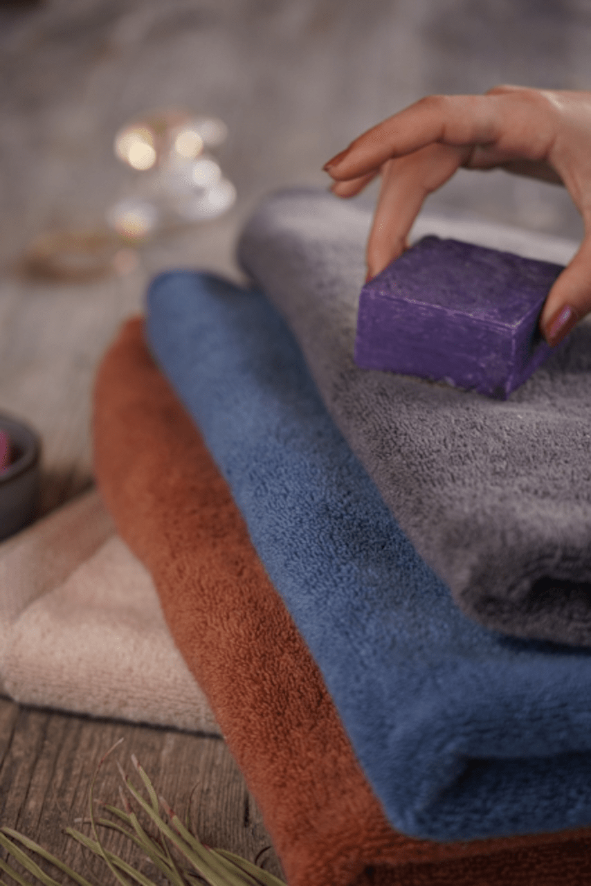 A bar of soap rests gently on Plush Lite Aegean Cotton towels, evoking the calming softness of organic luxury bath towels