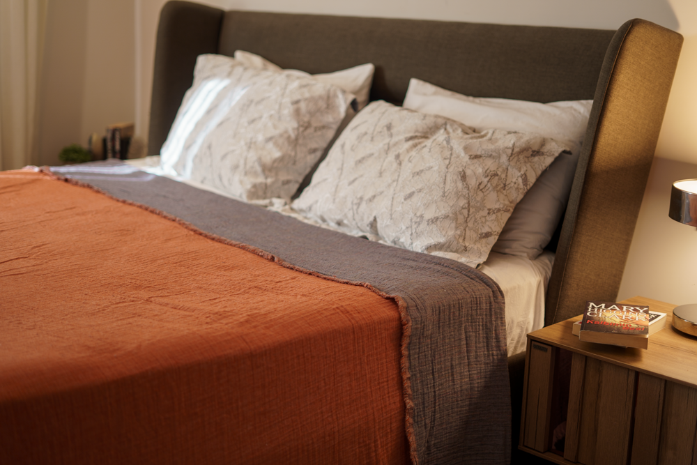 Reversible Muna organic gauze bed spread in Terra, draped on bed with soft texture, earthy hue, and elegance with organic cotton sheets.