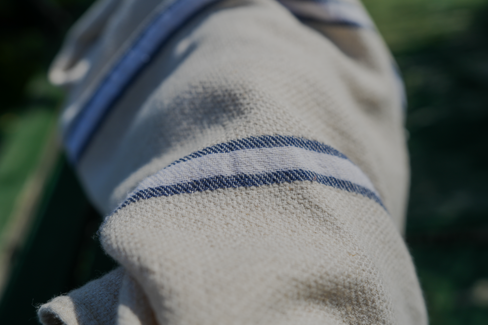 Blue and white Anakao 215 gram Aegean Cotton and Linen Turkish towel under the sunshine highlighting the soft texture and organic bath towel quality