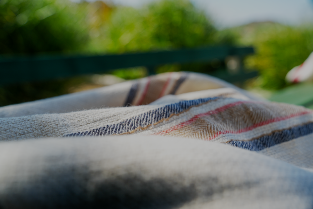 Close-up of Sand & Navy luxury organic Elba Turkish towel neatly placed on a bench table, highlighting its soft texture and elegant design
