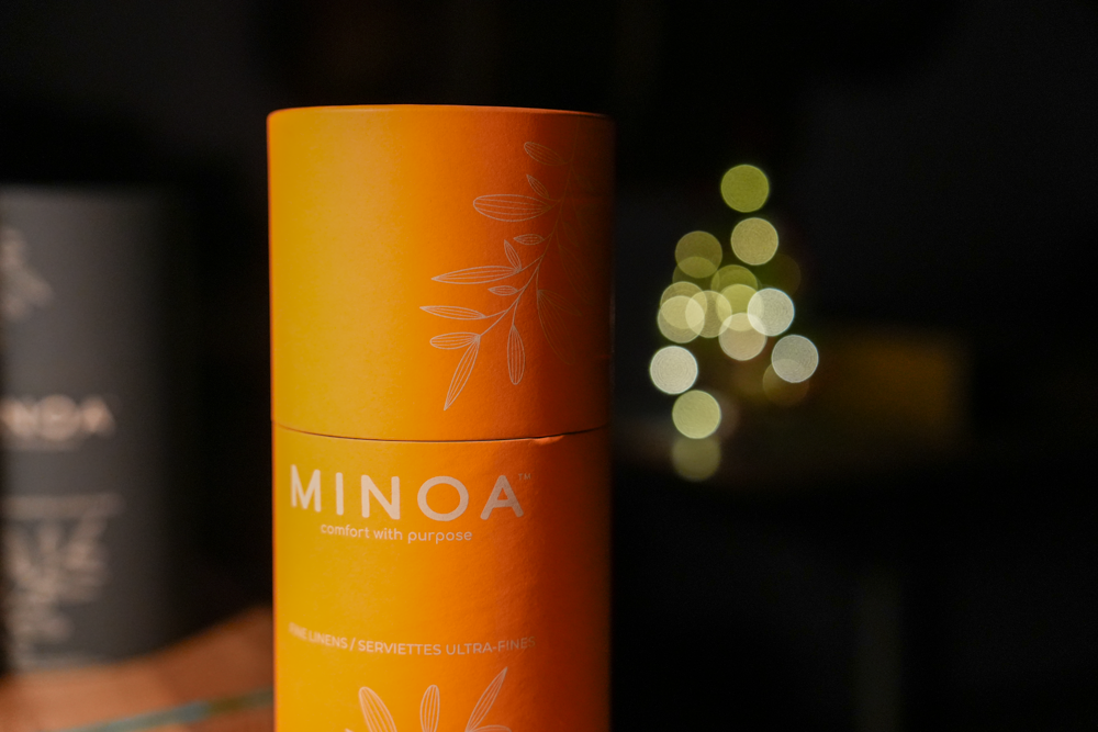 Close-up of Plush Lite 500-Gram Aegean Cotton luxury bath towels guest bath and hand towel set in a luxurious orange cylinder case with dark navy green case in the background