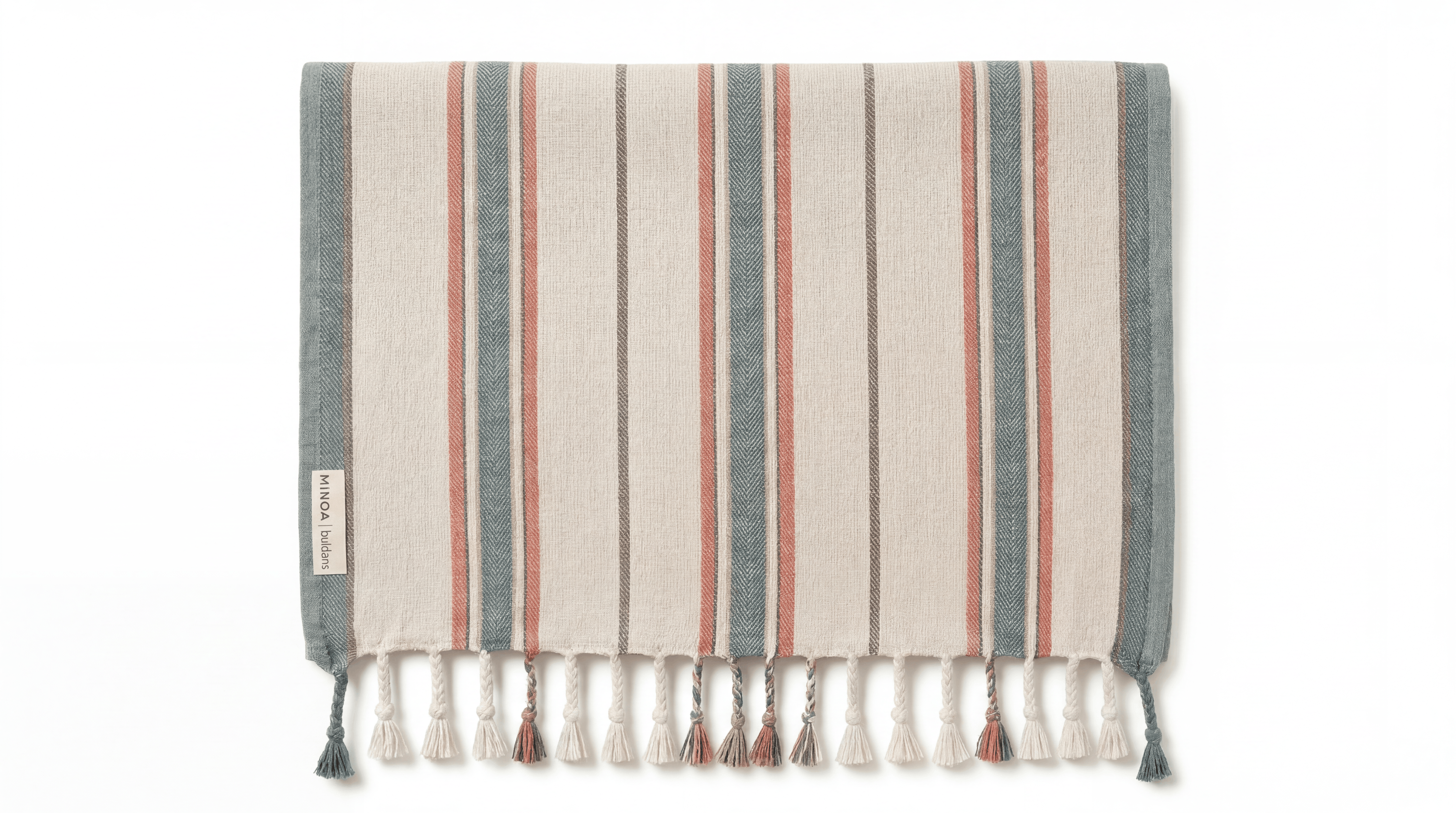 A striped Turkish towel with cream, slate blue, and terracotta stripes, finished with a fringed tassel edge. A small white label on the left edge reads 'Turkish Cotton'.