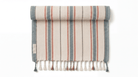 A rolled-up woven towel with vertical stripes in muted blue-gray, terracotta, and cream, finished with fringe tassels along the bottom edge, shown on a plain white background.