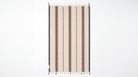 A rectangular woven rug with vertical stripes in beige, brown, and white, featuring white fringe tassels on the top and bottom edges, shown against a plain white background.