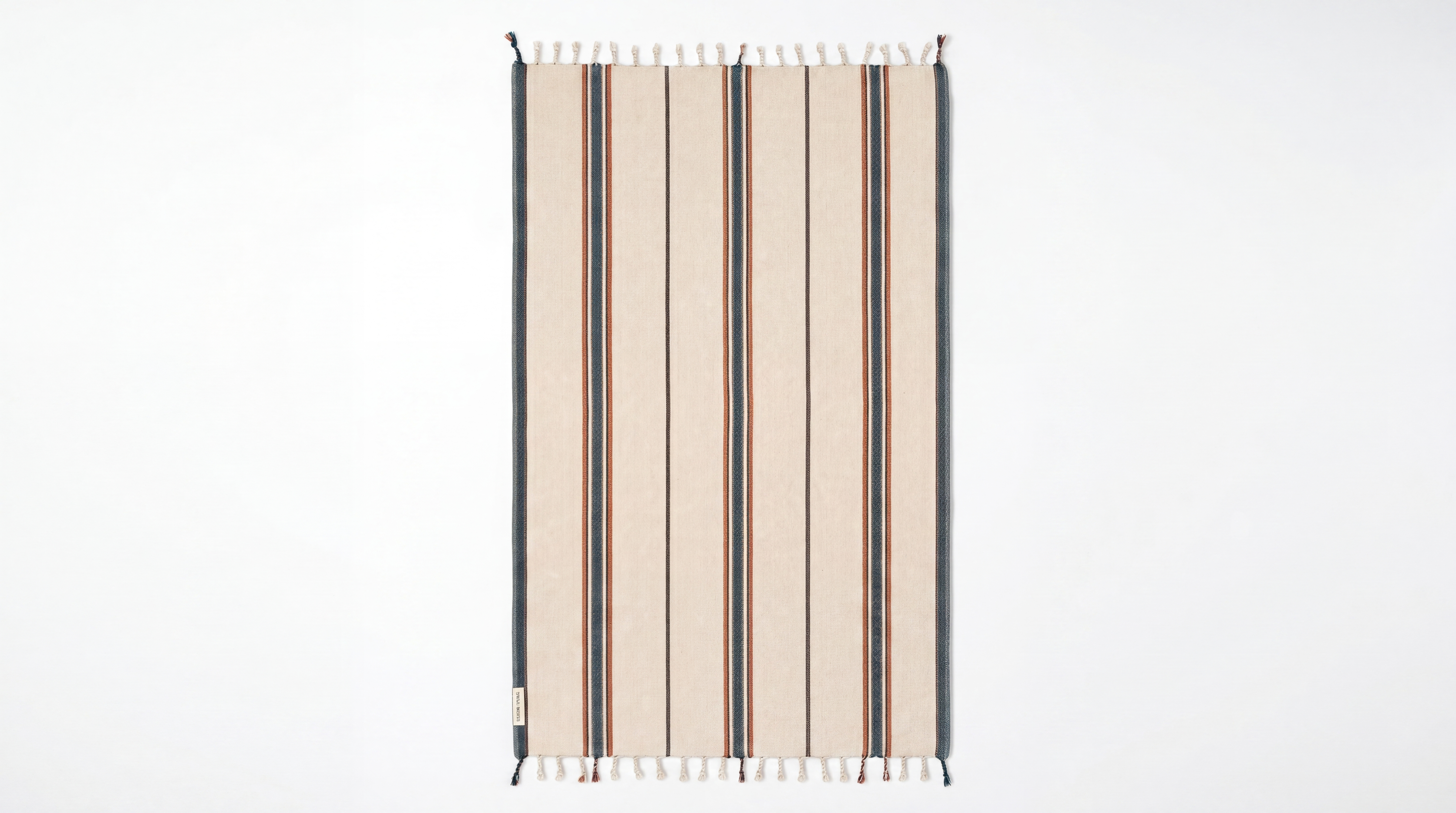 A rectangular woven rug with vertical stripes in beige, brown, and white, featuring white fringe tassels on the top and bottom edges, shown against a plain white background.