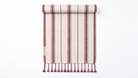 A rolled-up striped towel with fringe tassels at the bottom, shown on a clean white background. The fabric features vertical stripes in dusty rose, cream, and dark brown, with a small woven label on the left side.