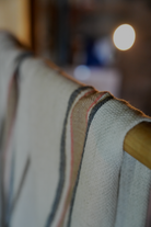Luxury and organic Sand & Navy Elba Turkish Towel hanging on a cloth hanger in a room
