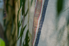 A close-up shot of the luxury organic Elba Turkish towel hanging on a cloth hanger outside, surrounded by green leaves for a natural vibe
