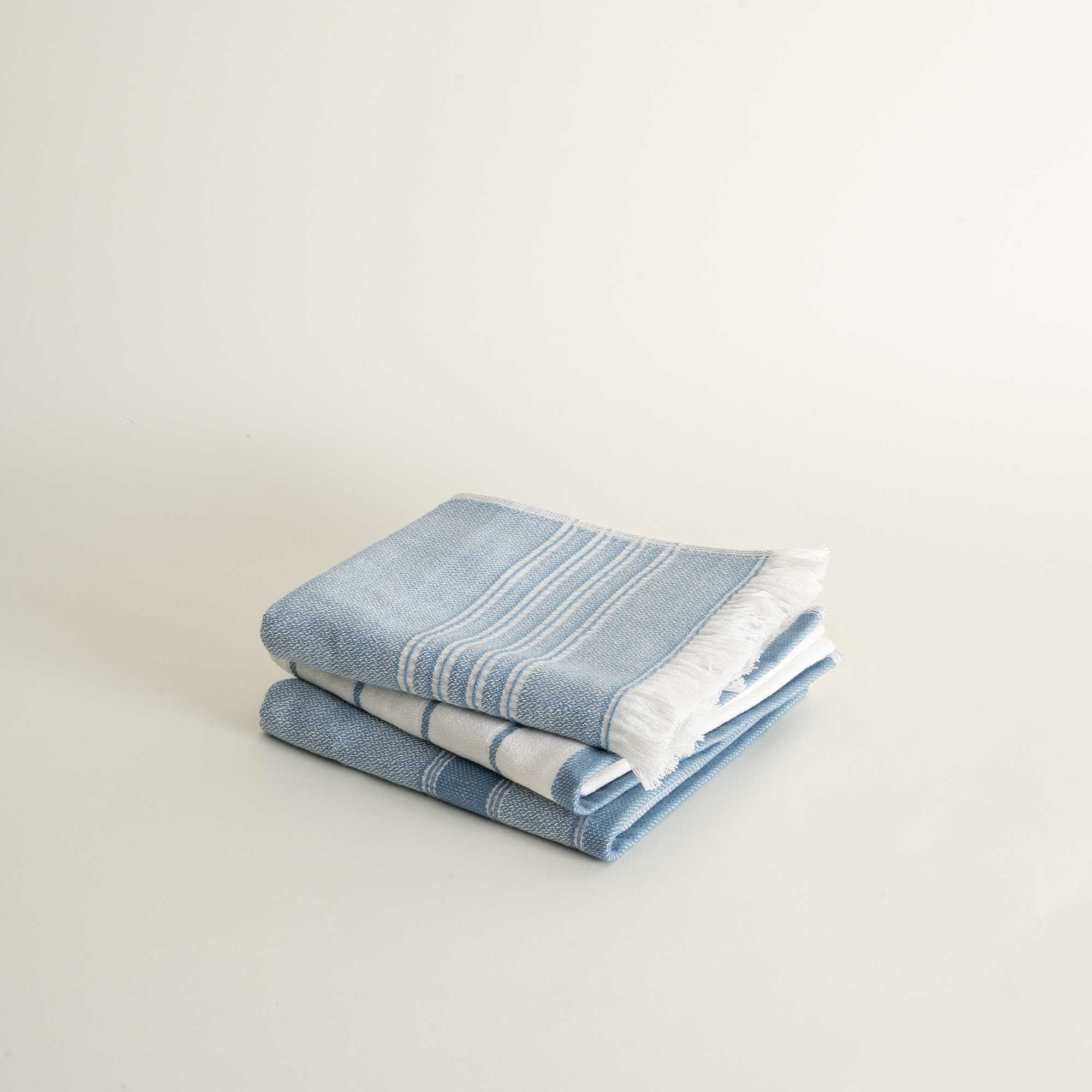 Stack of blue and white striped towels on a light background