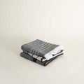 Stack of dark grey folded towels on a light beige background