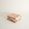 Stack of orange/red folded towels on a light beige background