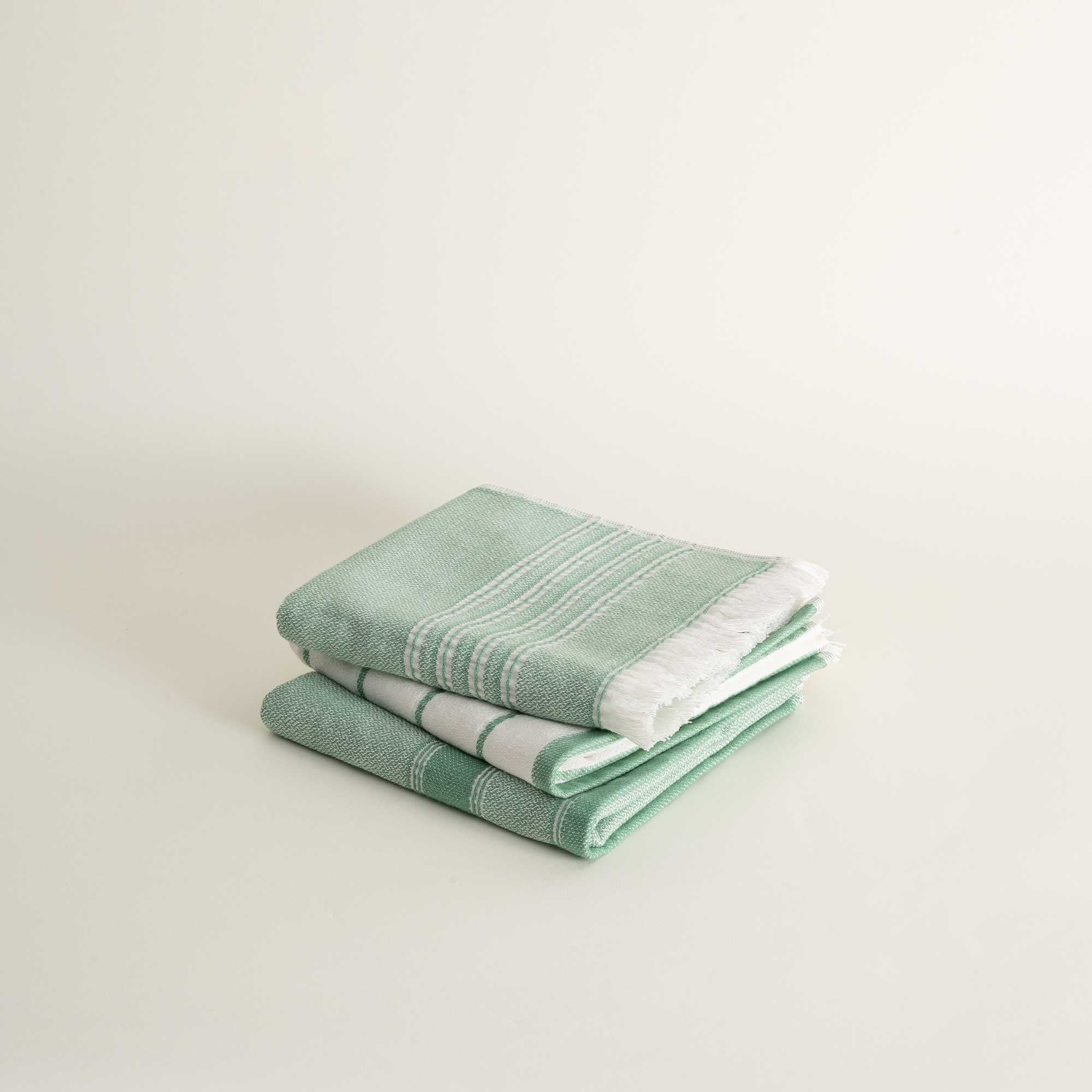 Stack of green towels on a light beige background