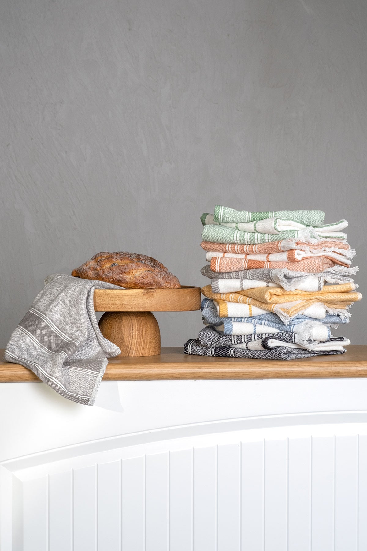 Elis Organic Aegean Cotton Kitchen Towel set of 3, featuring Lime Breeze, Silver Symphony, Midnight Velvet, Spice Serenade, Lemon Zest, and Serene Sky, neatly folded beside a loaf of bread