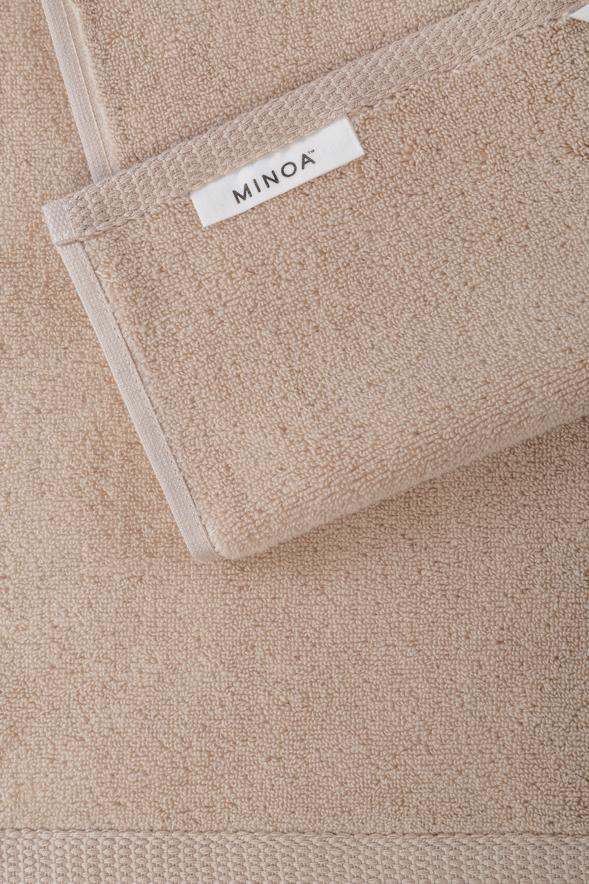 Close-up of a beige towel with a visible brand label on a matching background.