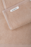 Close-up of a beige towel with a visible brand label on a matching background.
