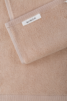 Close-up of a beige towel with a visible brand label on a matching background.