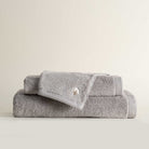 Three folded Jasper 600-gram organic Aegean cotton luxury bath, hand, and washcloth towels in Silver Symphony, showcasing soft plush texture, cool tone, and luxurious fabric