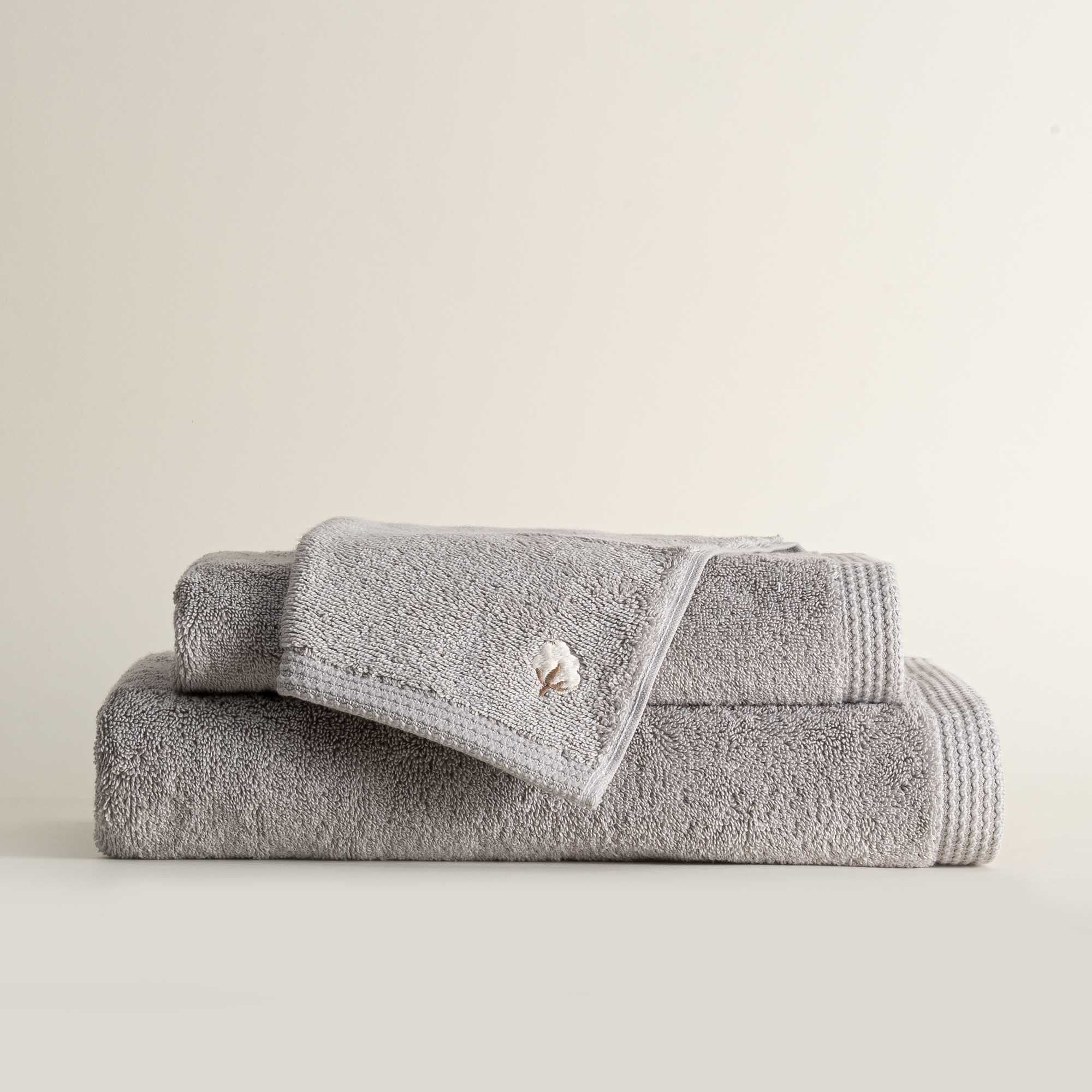 Three folded Jasper 600-gram organic Aegean cotton luxury bath, hand, and washcloth towels in Silver Symphony, showcasing soft plush texture, cool tone, and luxurious fabric