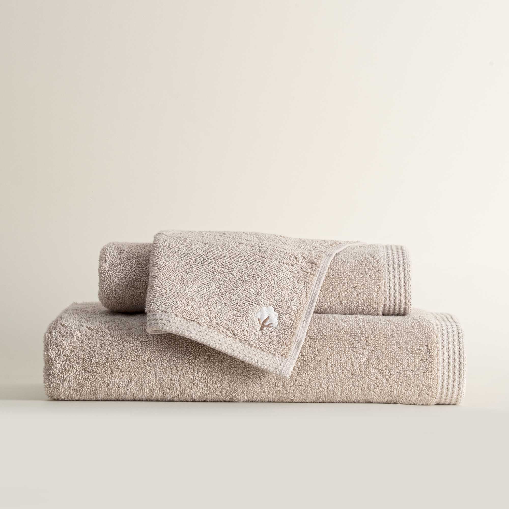 Three folded Jasper 600-gram organic Aegean cotton luxury bath, hand, and washcloth towels in Vanilla Embrace, showcasing soft plush texture, warm color, and luxurious fabric