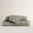 Three folded Jasper 600-gram organic Aegean cotton luxury bath, hand, and washcloth towels in Mossy Muse, showcasing soft plush texture, earthy tone, and luxurious fabric