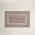Rectangular bath mat with textured border on a plain background