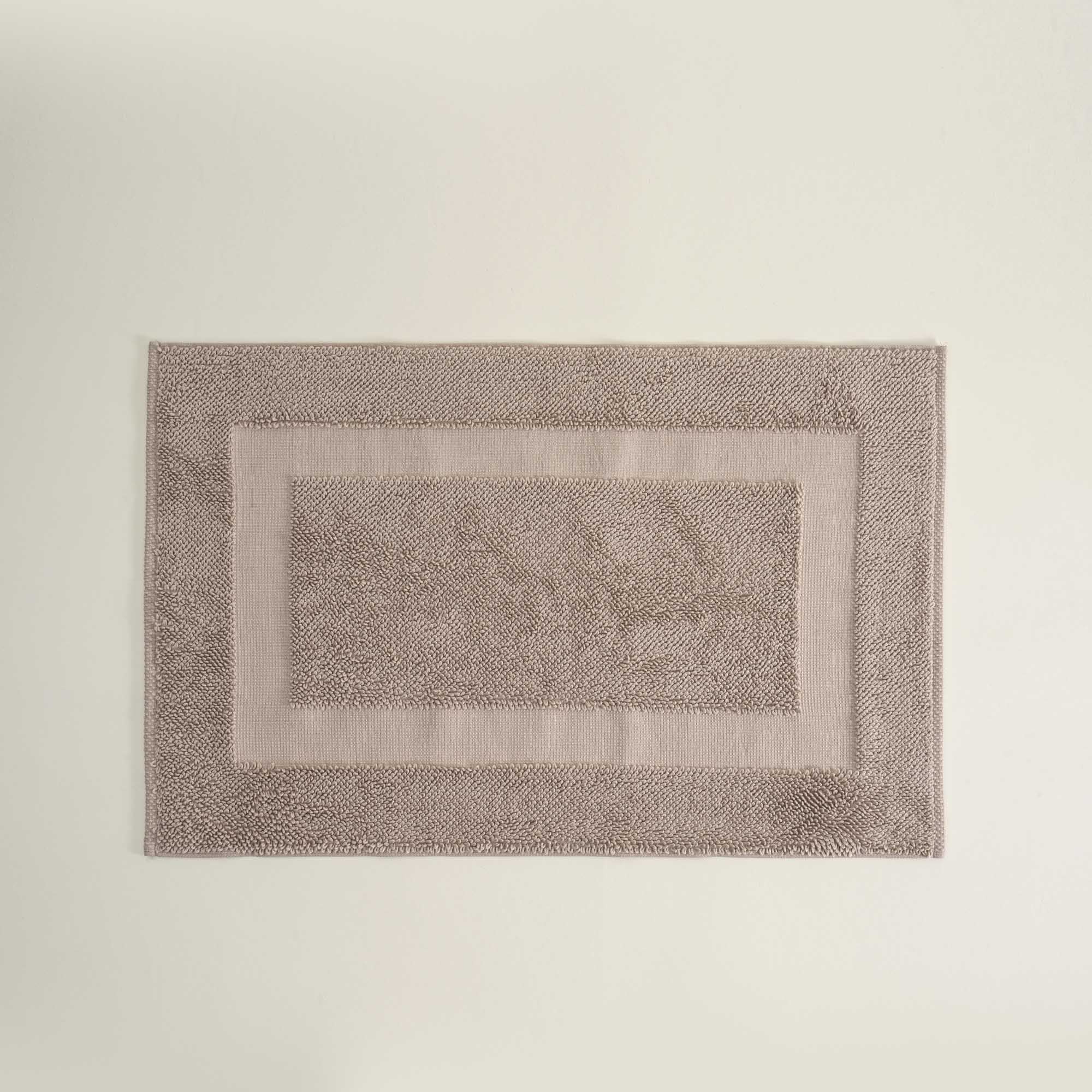 Rectangular bath mat with textured border on a plain background
