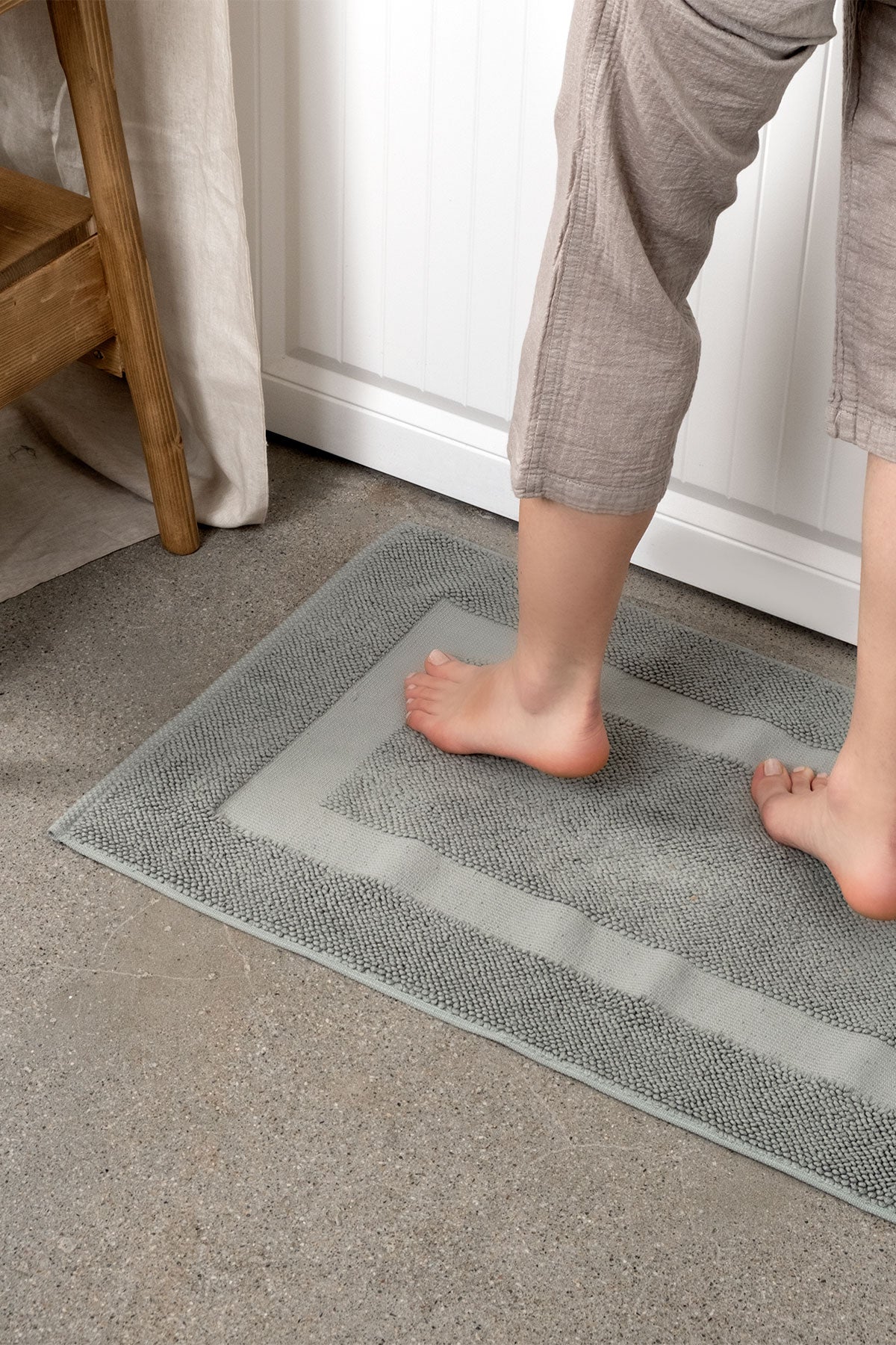 Kaia Aegean Cotton Bath Mat in Meadow Sage, gently stepped on, showcasing its soft texture, soothing colour, and luxurious fabric
