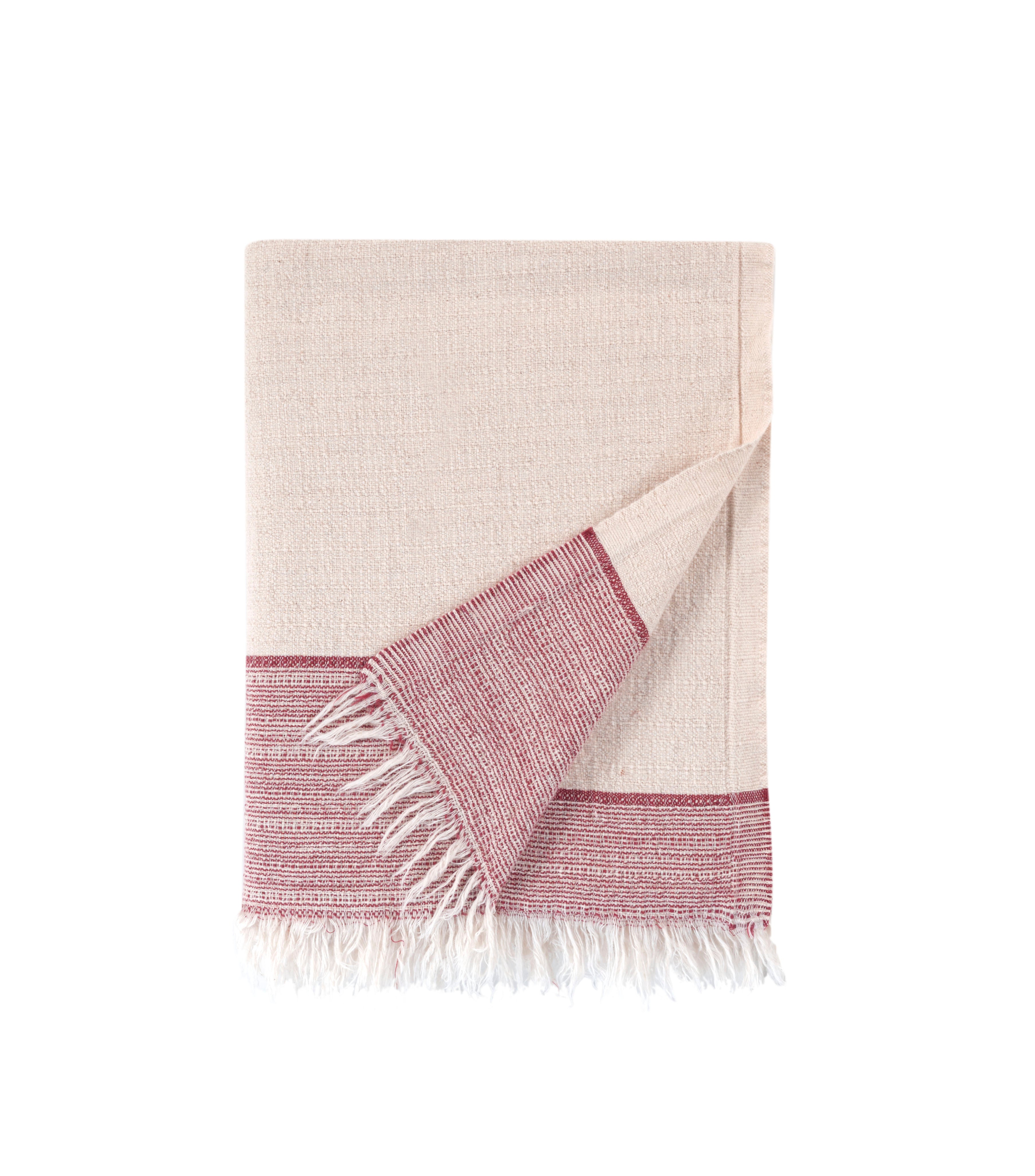 Beige and pink woven towel with fringes on a white background