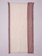 A rectangular cream-colored woven towel with fringed edges and a wide dusty rose patterned border, laid flat against a light gray background.