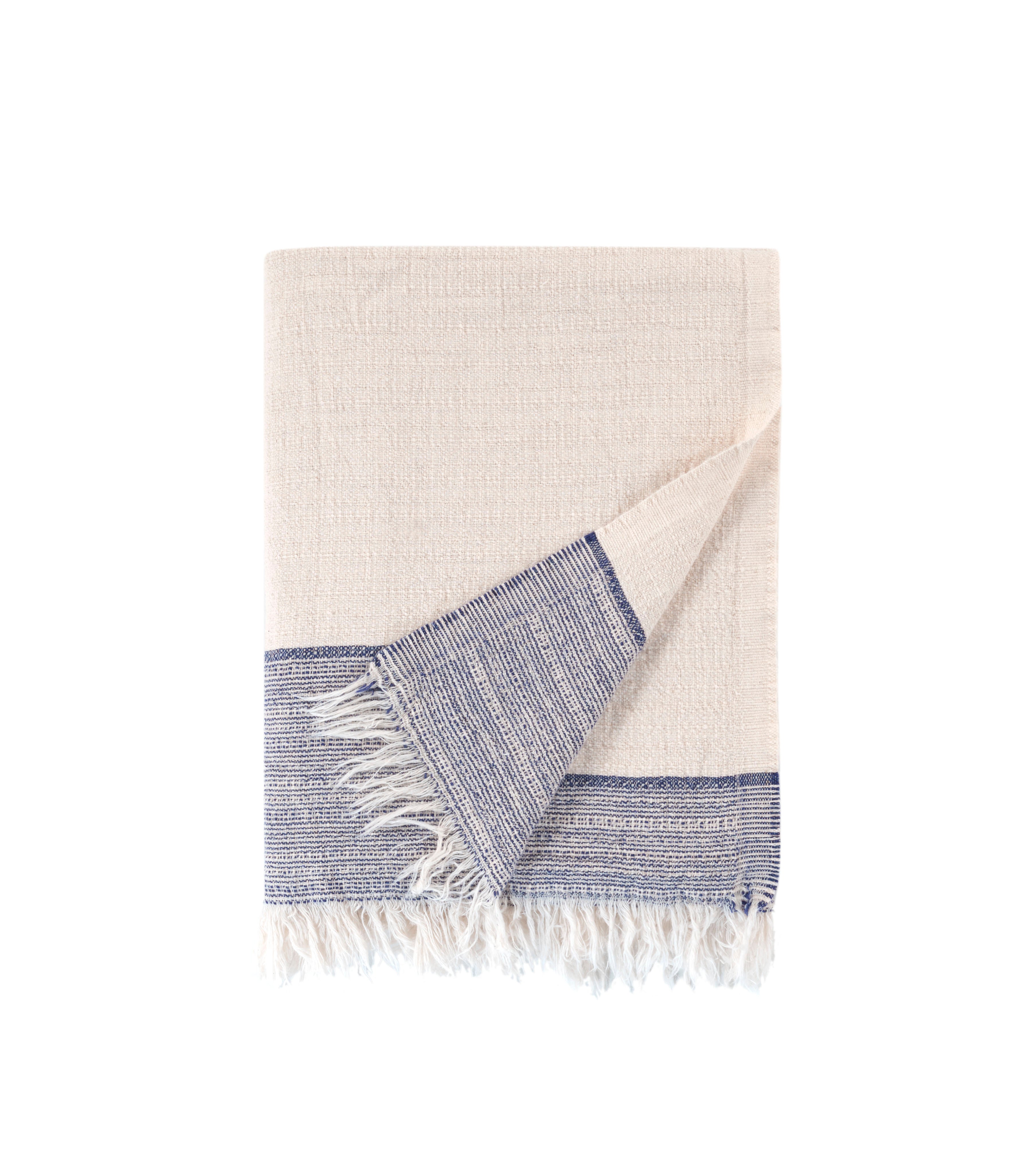 Beige towel with blue border and white fringe on a white background