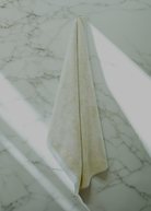 A Monte Rosa towel hanging on the wall, in the beige color.