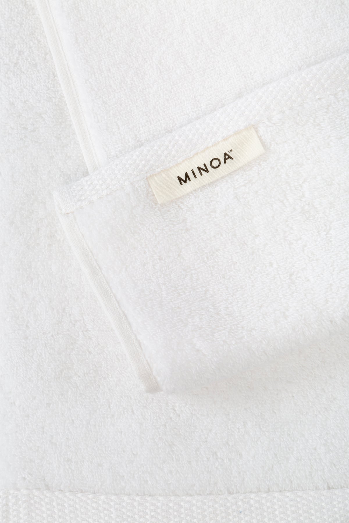 Close-up of a white towel with 'MINOA' label