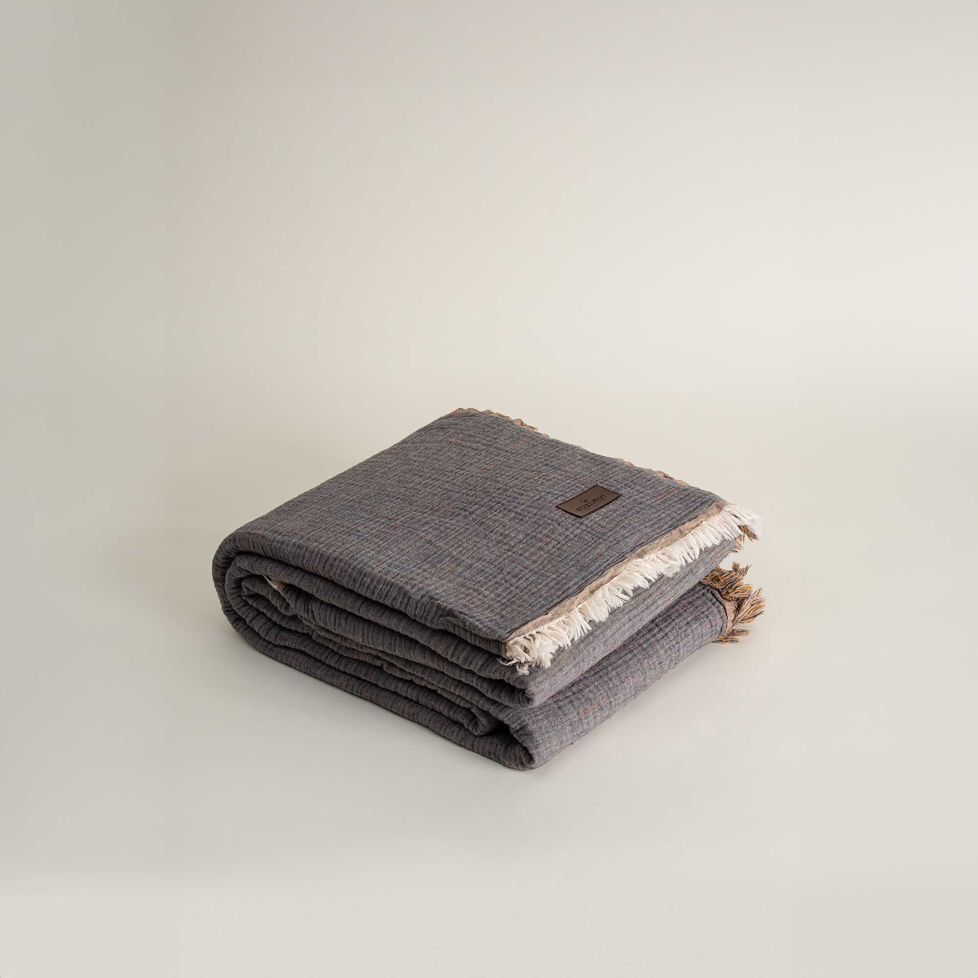 Neatly folded reversible Muna organic gauze bedspread in Mustard, soft texture, vibrant hue, designed to pair with organic cotton sheets.