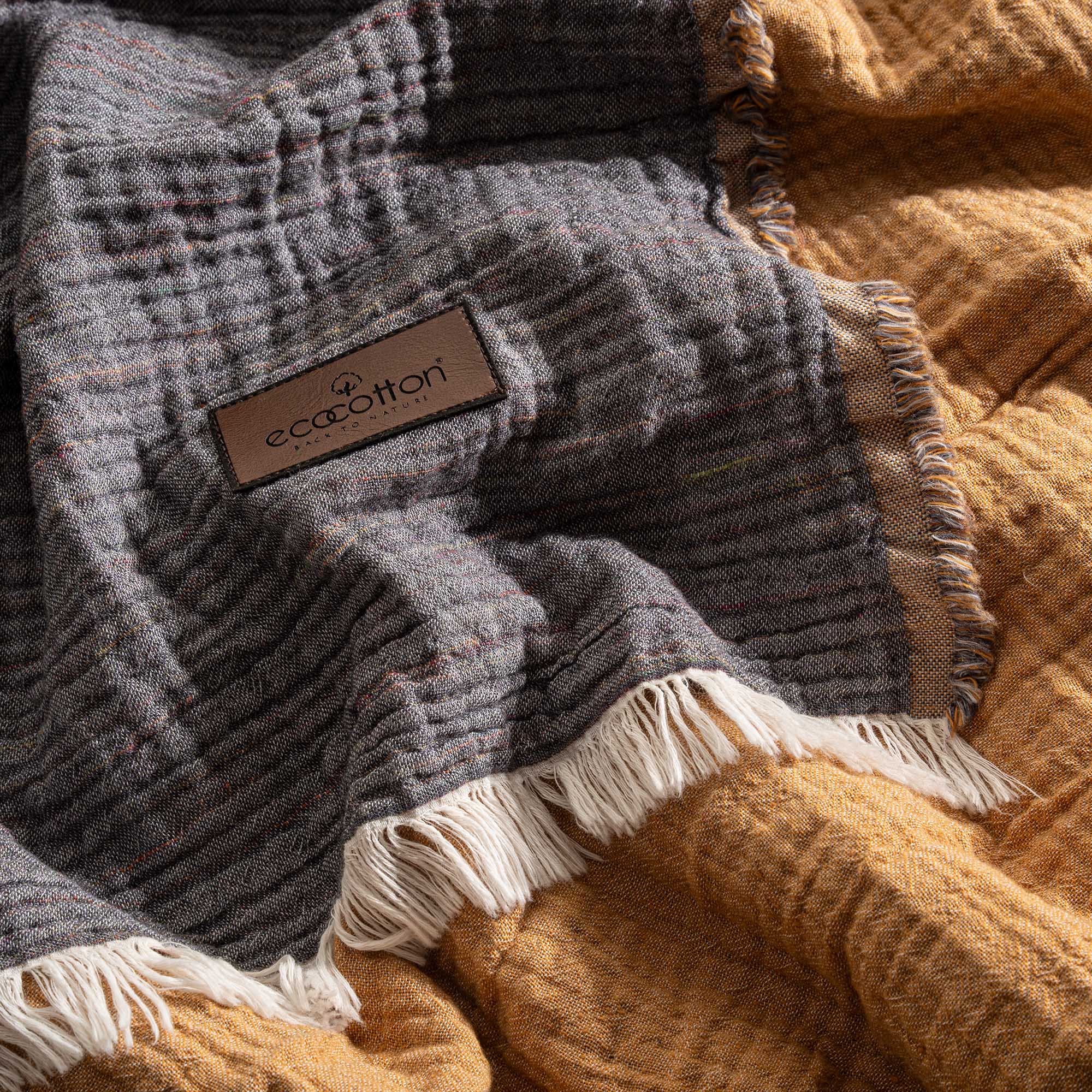 Close-up of the Reversible Muna organic gauze bedspread in Mustard, soft texture, rich color, fine craftsmanship with organic cotton sheets.