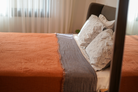 Reversible Muna organic gauze bed spread in Terra, draped on bed, soft texture, warm earthy hue, elegant design with organic cotton sheets.