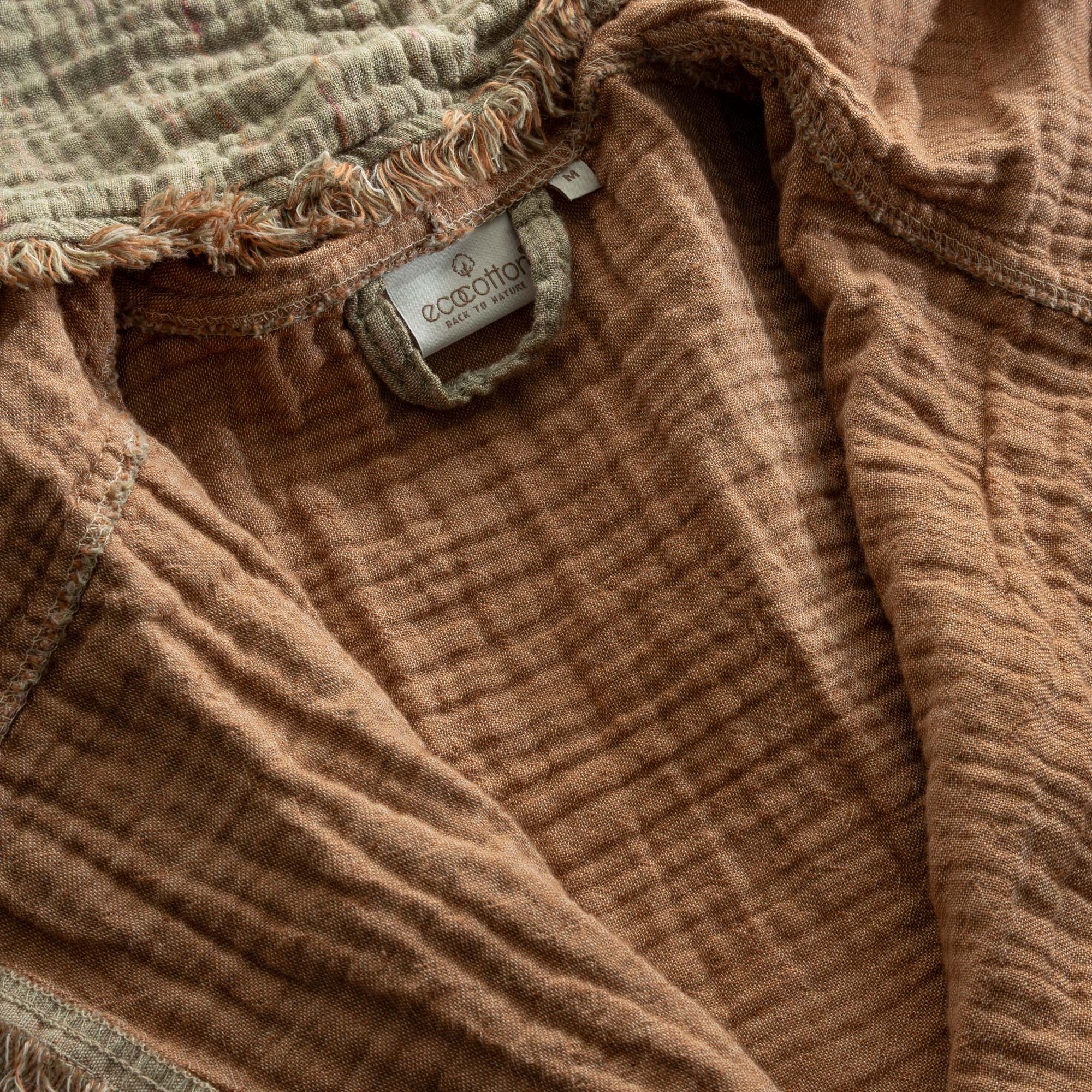 Tag on Men's Muna Organic Aegean Cotton Gauze Two Sided Robe in Khaki Terra, highlighting collaboration with Ecocotton and commitment to sustainable materials.