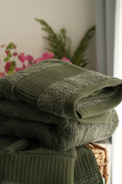 Stack of green towels with a blurred floral background