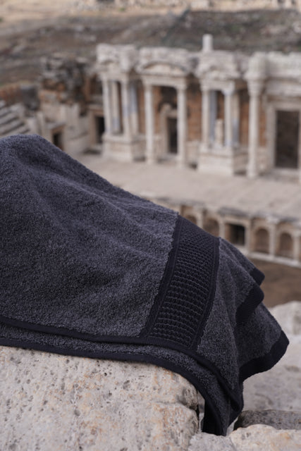 Dark gray towel on stone steps with ancient ruins in the background